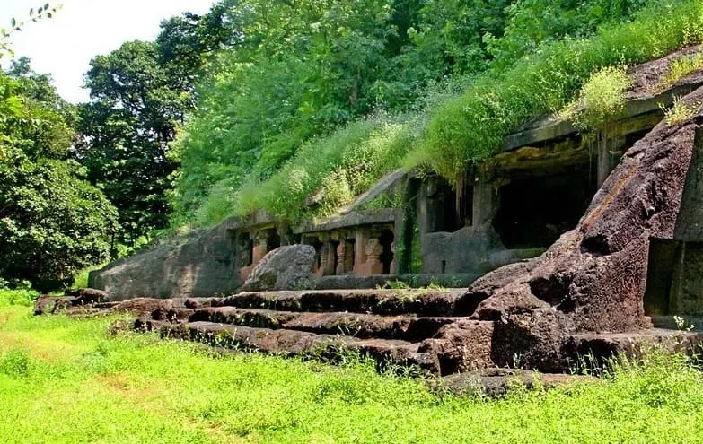 Moss-covered rock-cut Panhalekaji caves surrounded by green forest